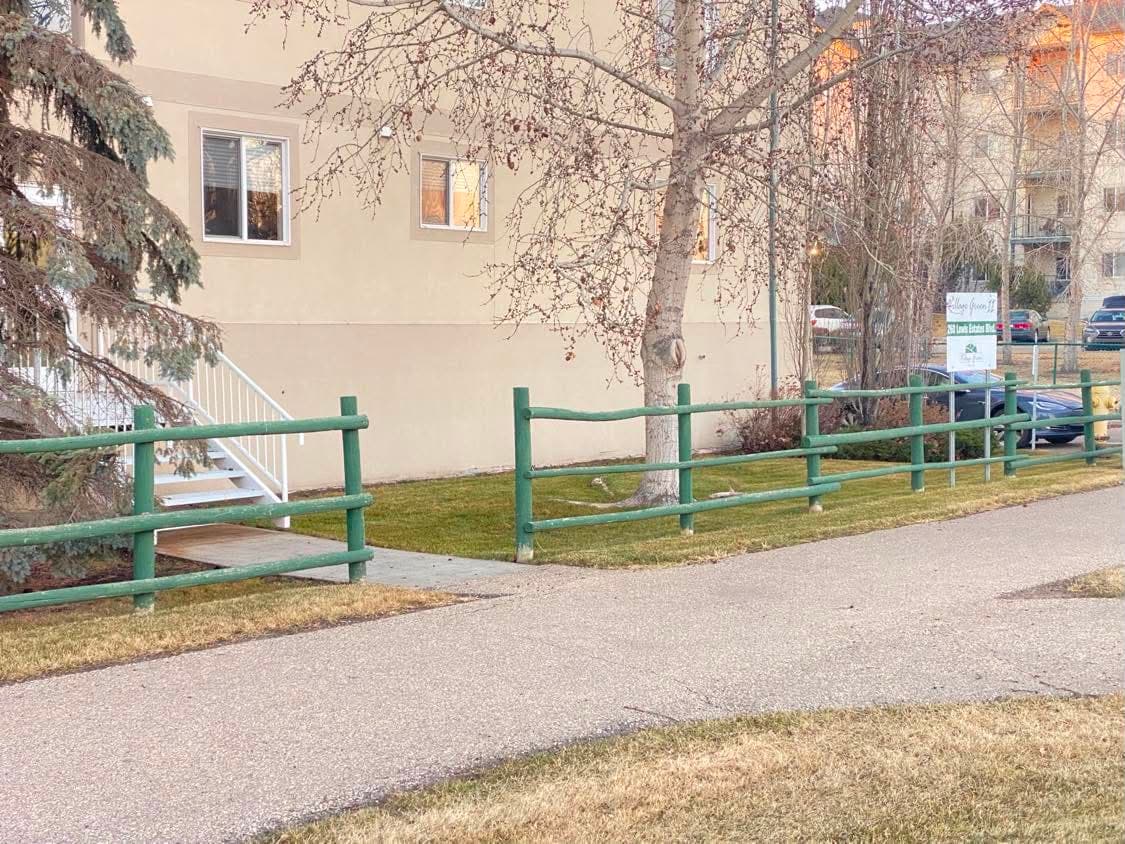 Tidy condominium grounds with a mown lawn, swept walkway and mature spruce trees